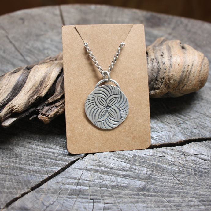 four petal flower stamped on silver disc necklace